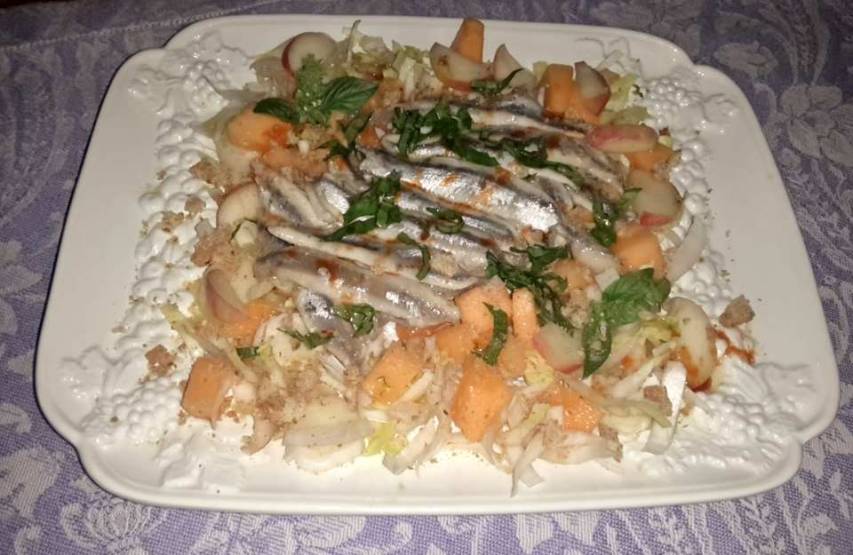 Insalata di belga, melone e pesca con alici marinate e briciole di frisella